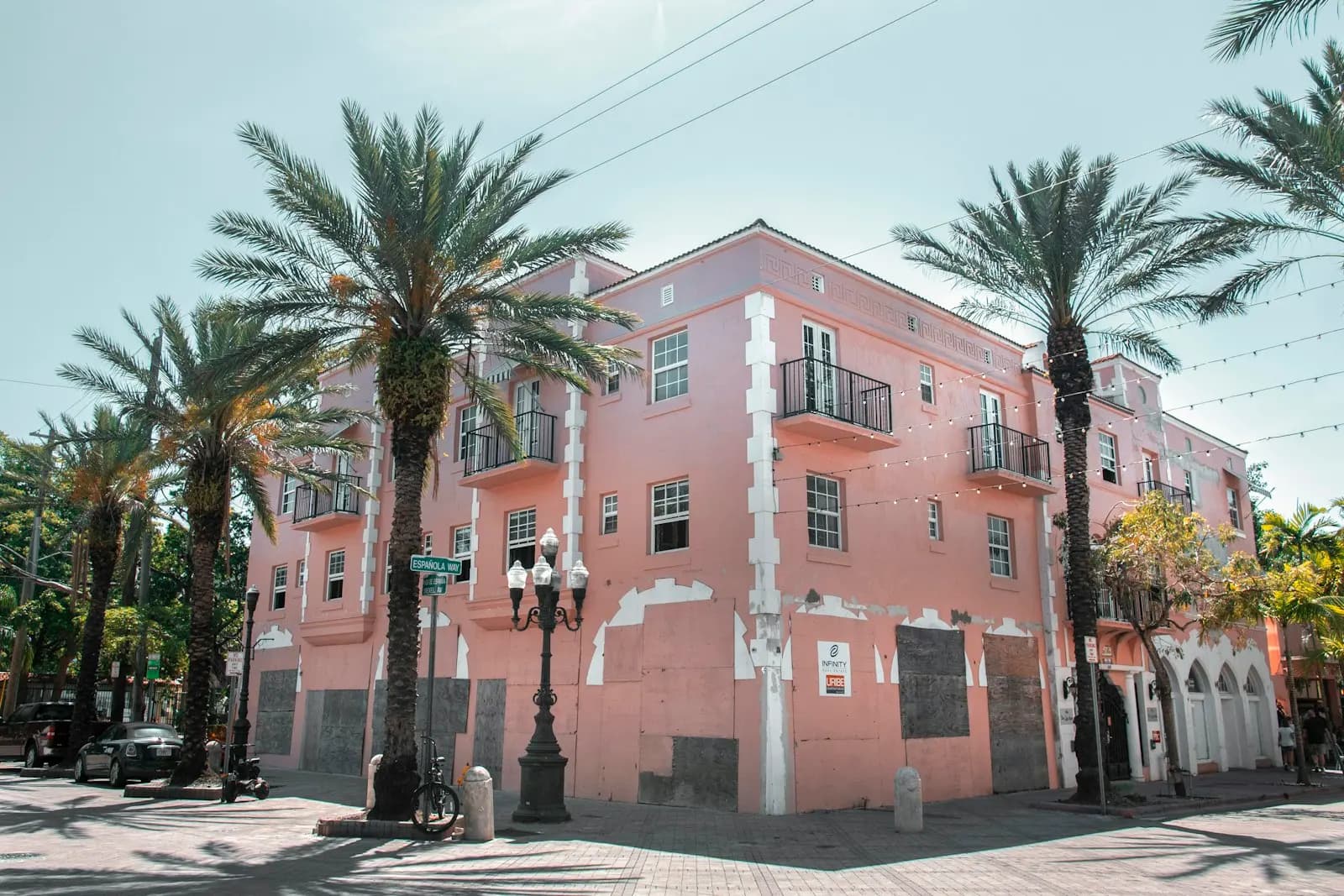 Miami’de Little Havana’da bir köşe başındaki pembe apartman; önünde palmiyeler ve sokak lambaları.